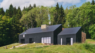 Exterior of the house which is set on grass and in front of trees