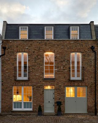 Brick face double story house with six windows and one door.