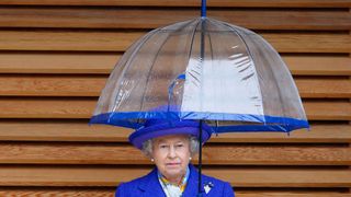 Queen Elizabeth shelters under her umbrella as she visits the new National Tennis Centre, Roehampton
