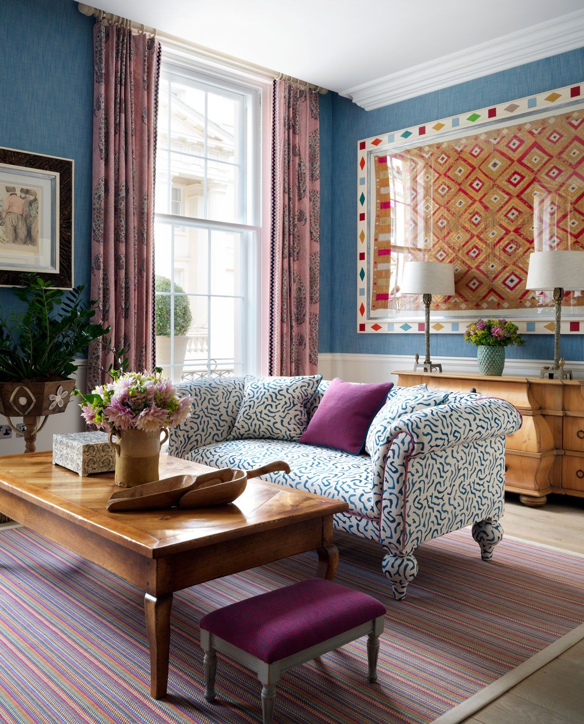 Living room with sofa and coffee table in foreground, window and lamps in background