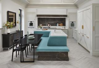 A New Deco kitchen with teal colored kitchen island, black seating and light herringbone effect flooring