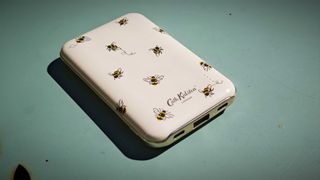 A Cath Kidston branded power bank with bee patterns on a blue-green table