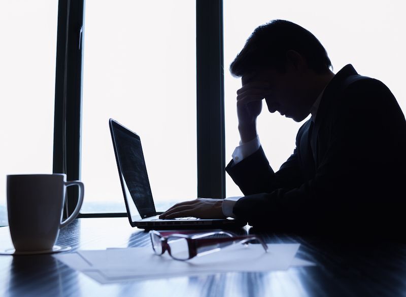 A man sits in a dark office, looking depressed.