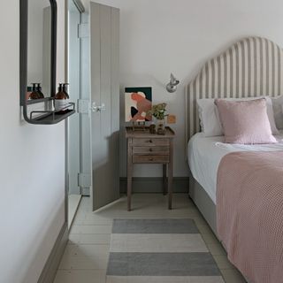 A bedroom with a statement vertically striped headboard and a runner rug next to the bed withh wide horizontal stripes