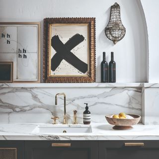 A kitchen with black cabinets and marble-effect worktop and splashback