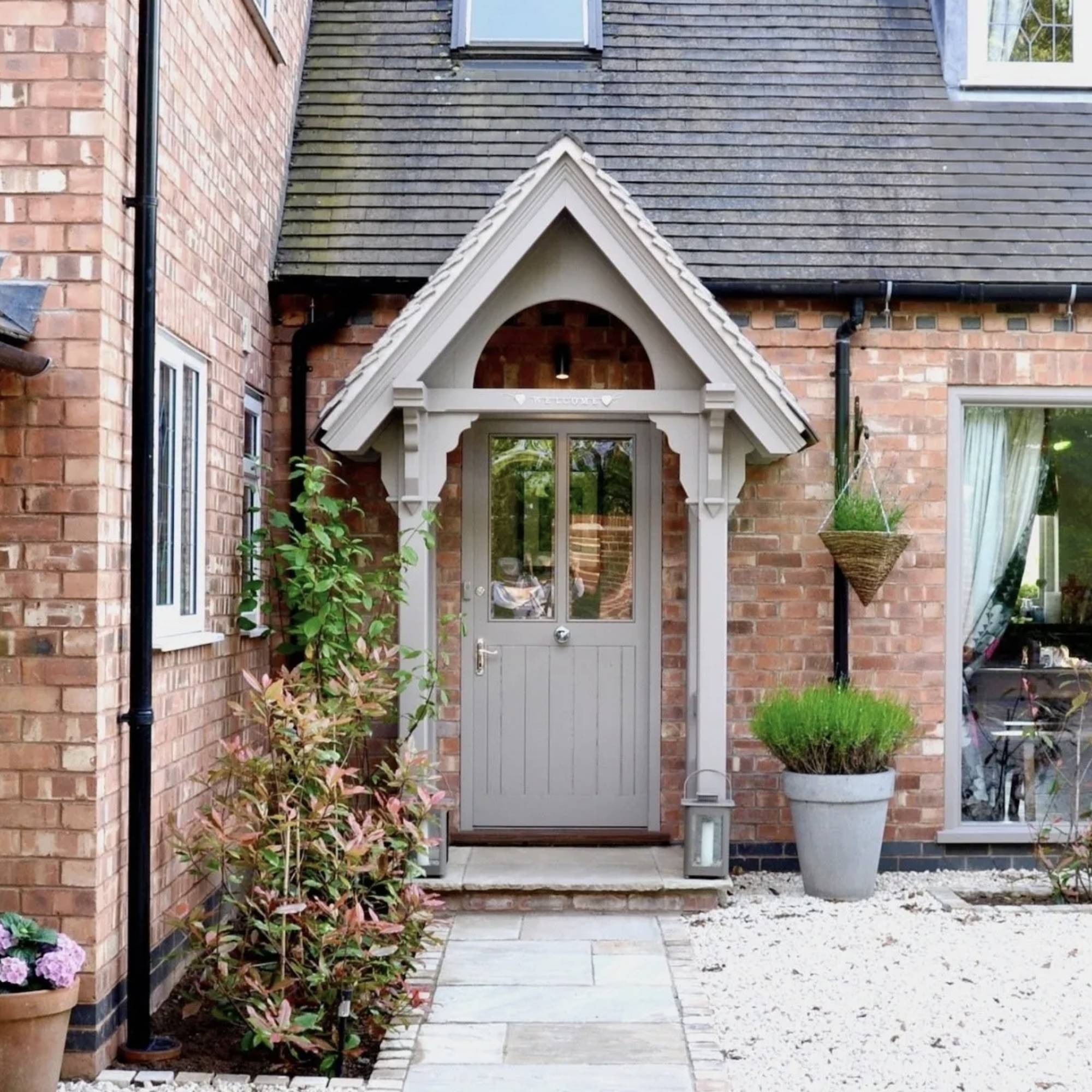 grey wooden porch to brick traditional house with stone path