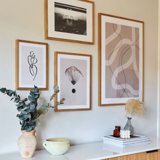 Artwork hung above white and cane dresser decorated with houseplant and decorative objects