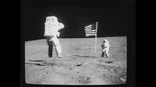 During the first EVA of NASA's fifth lunar landing mission, astronaut John W. Young, commander of the Apollo 16 mission, salutes the United States flag while jumping from the moon's surface.
