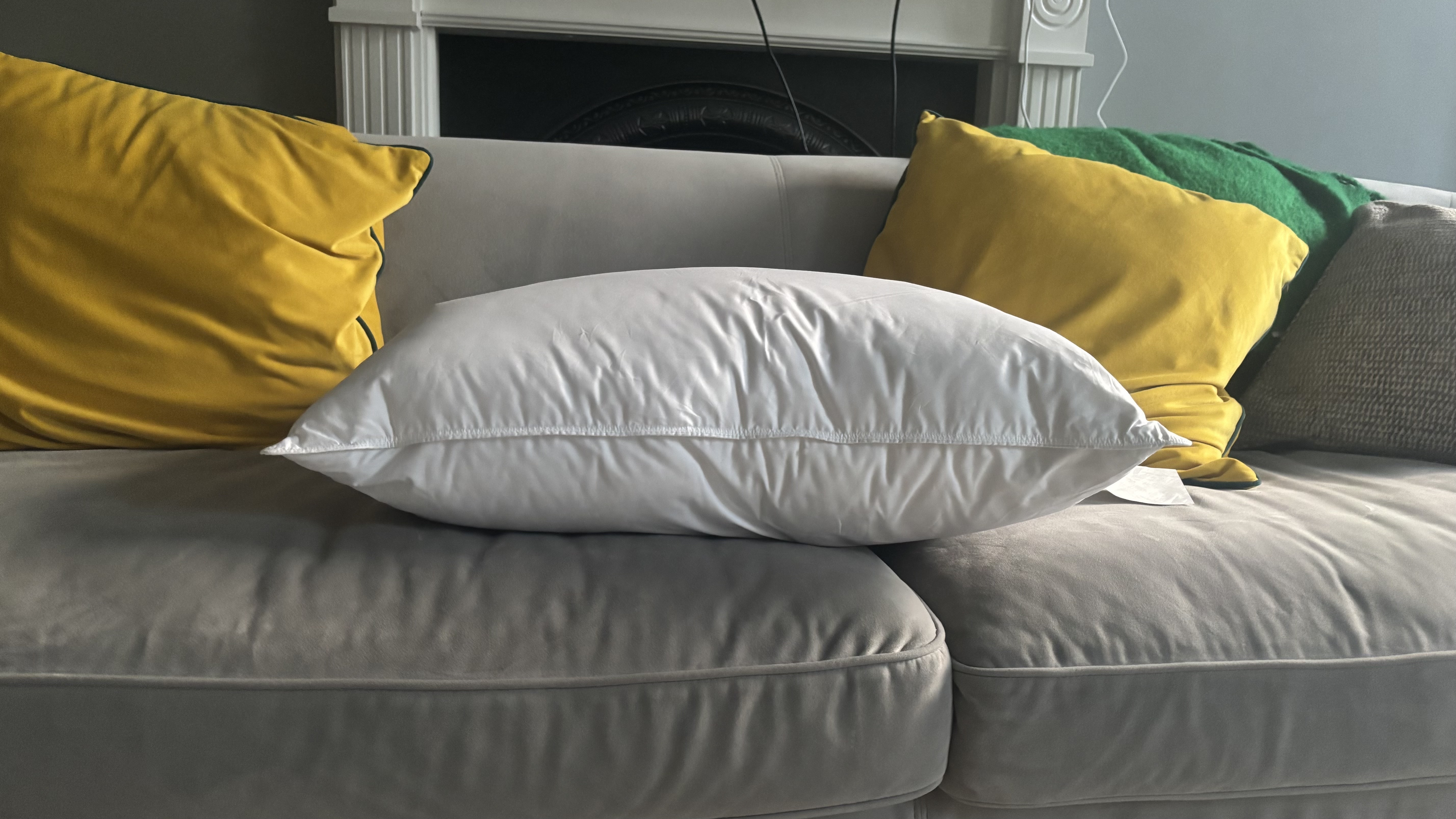 Helix Down &amp;amp; Feather Pillow on a grey couch with bright green cushions.