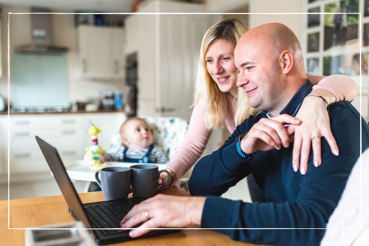 married couple looking at laptop with baby in a highchair next to them