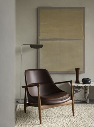 A pale green wall and green and yellow wallhanging with a brown leather chair in front