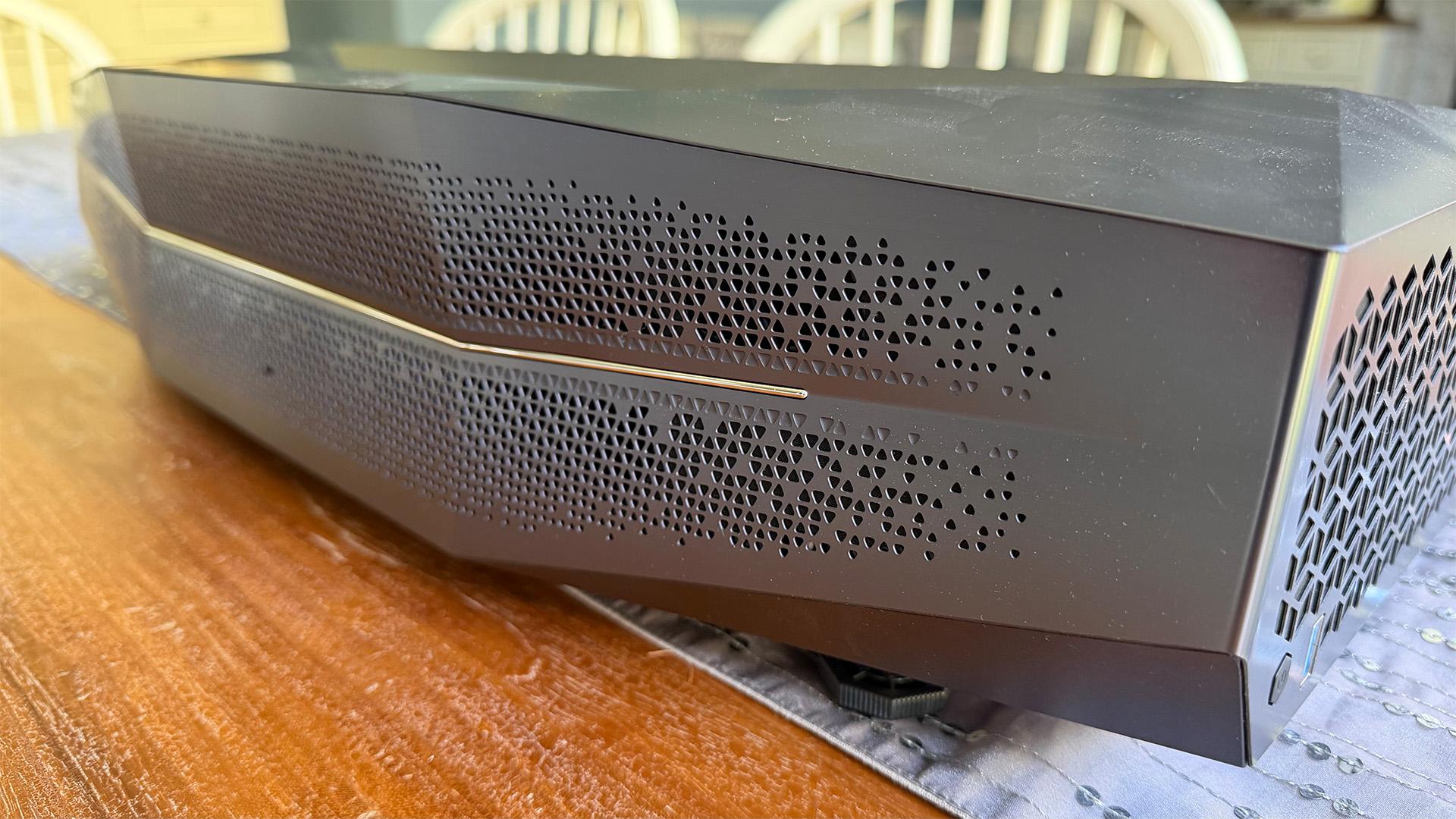 AWOL Vision Aetherion Max ultra short throw projector on wooden dining table slight side angle