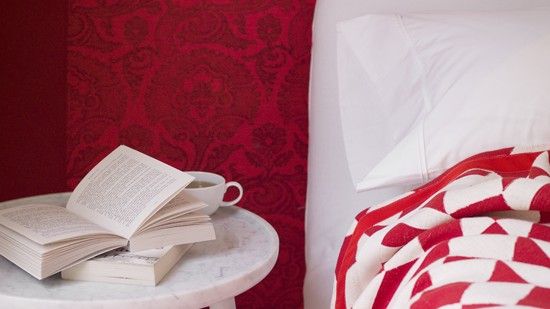 bedroom with red wall and red throw on white bed