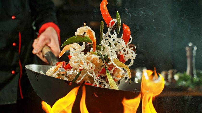 A wok cooking over a gas flame 