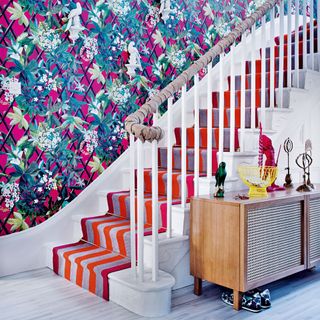 living room with floral printed wall and white staircase