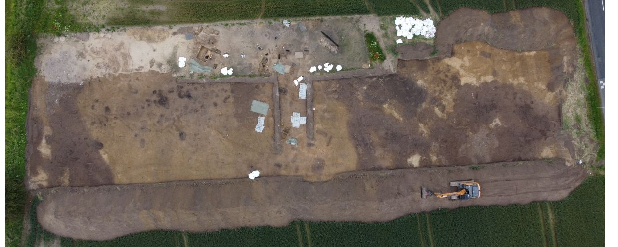 A bird's-eye view of the dirt burial ground excavation in a grass field.