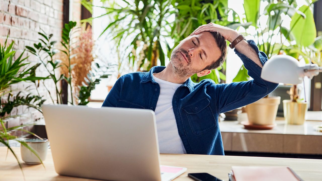 A man stretching at his desk 