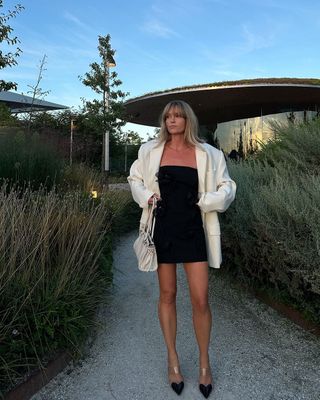 @_jeanettemadsen_ wearing a black mini dress, heels and a white blazer