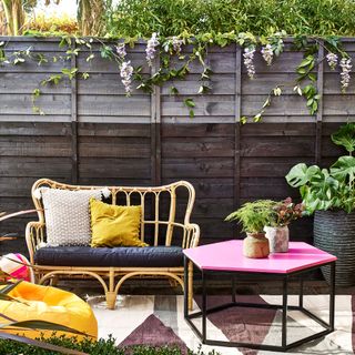Grey fence with yellow wire bench and pink stools