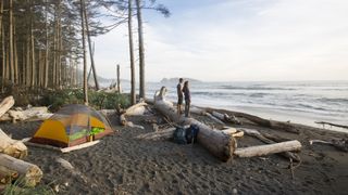 A couple on the beach looking out to see with a tent behind them