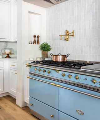 blue range cooker in a tiled alcove in a white traditional kitchen with a storage niche