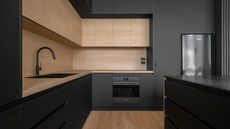 black kitchen with timber upper cabinets and timber flooring