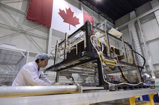 A technician removes the infrared test rig surrounding the asteroid-hunting NEOSSat after the final thermal vacuum test at the David Florida Laboratory located in Ottawa, Ontario. NEOSSat is a dual-mission microsatellite designed to detect potentially hazardous Earth-orbit-crossing asteroids and track objects that reside in deep space. It is also the first implementation of Canada's generic multi-mission microsatellite bus. It will launch aboard an Indian Polar Satellite Launch Vehicle on Feb. 25, 2013.