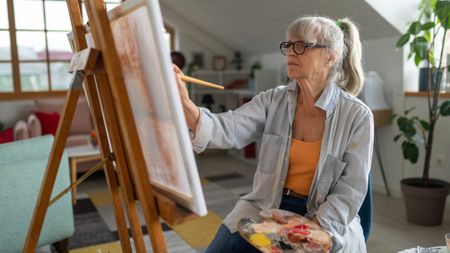 Mature woman painting on a canvas in her apartment