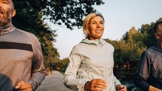 Woman running along path with two men