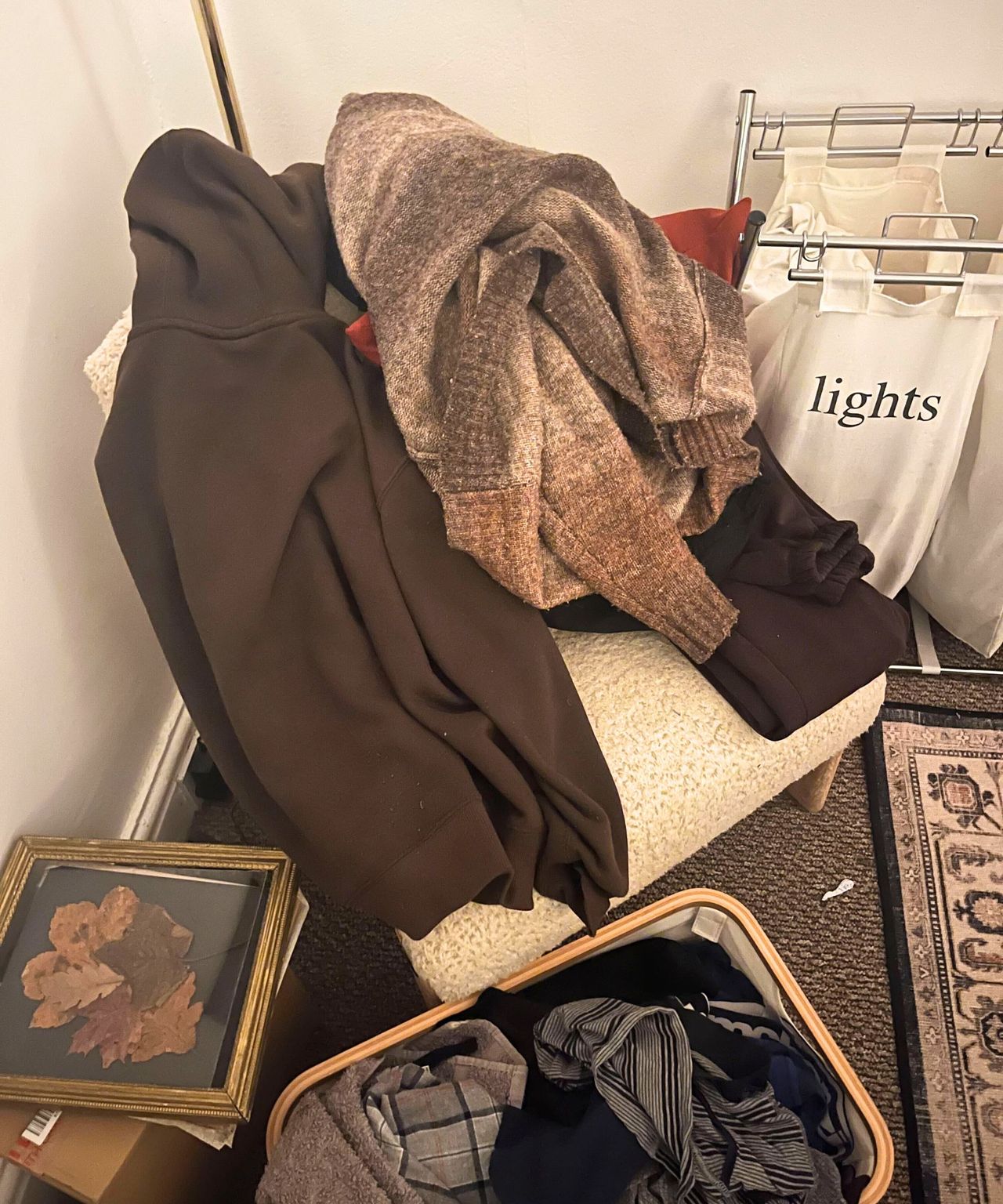 A messy pile of clothes on a chair in the corner of a room