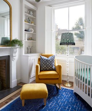 white small nursery with a fireplace and yellow armchair with blue rug