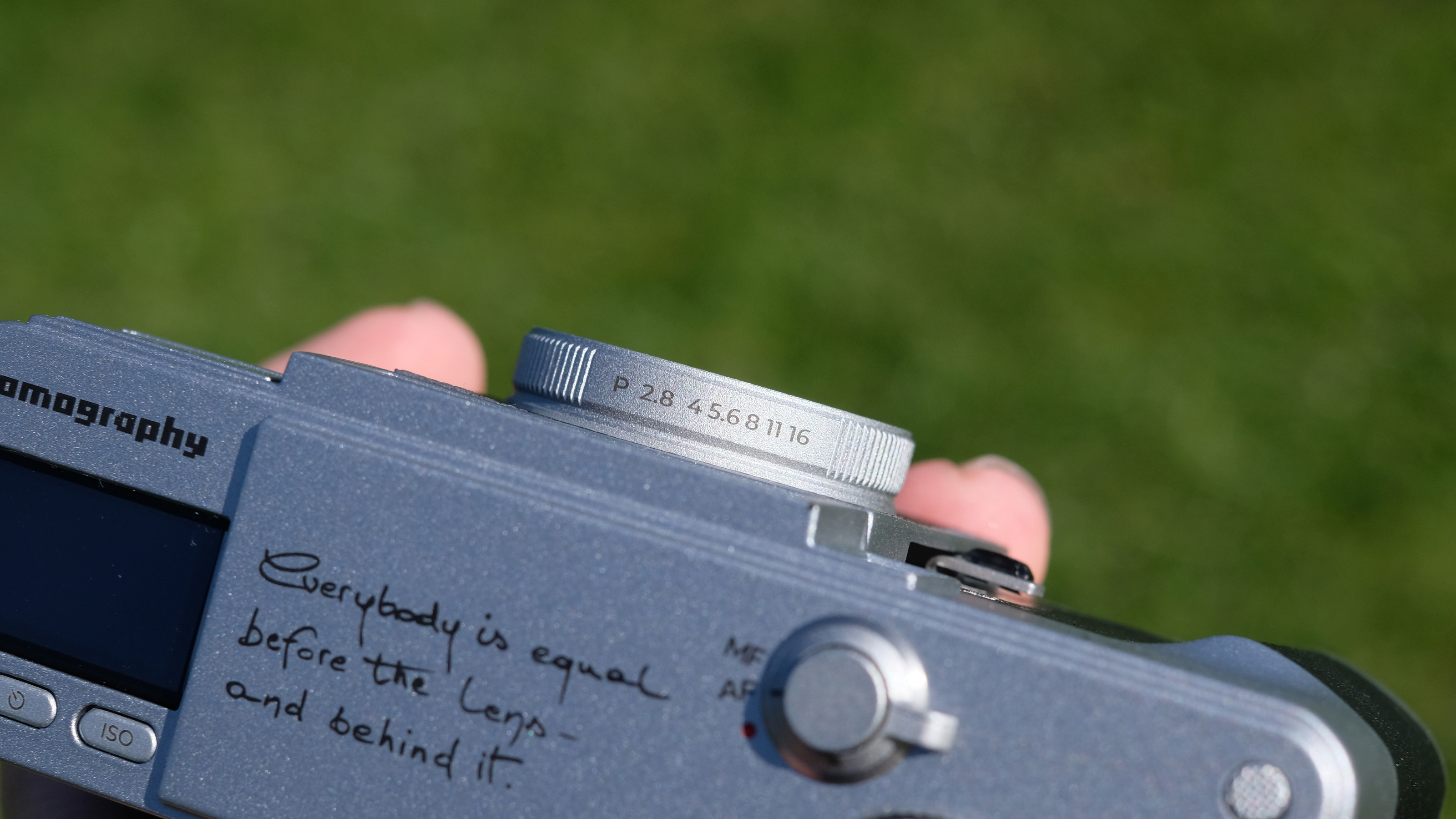 Photograph of the Lomography Lomo MC-A, with grass visible in background, showing detail of lens aperture ring