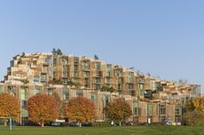 Exterior of multi-storey residential building with grass landscaping and spaced out trees in the forefront.