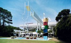 The 1986 house’s rectangular sunscreen represents a beach umbrella, while the pool area is framed by two sculptures 