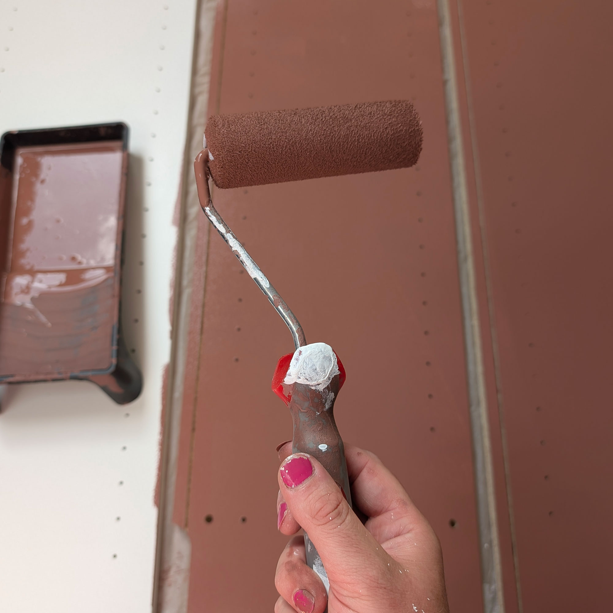 Red paint on wood panel and paint roller