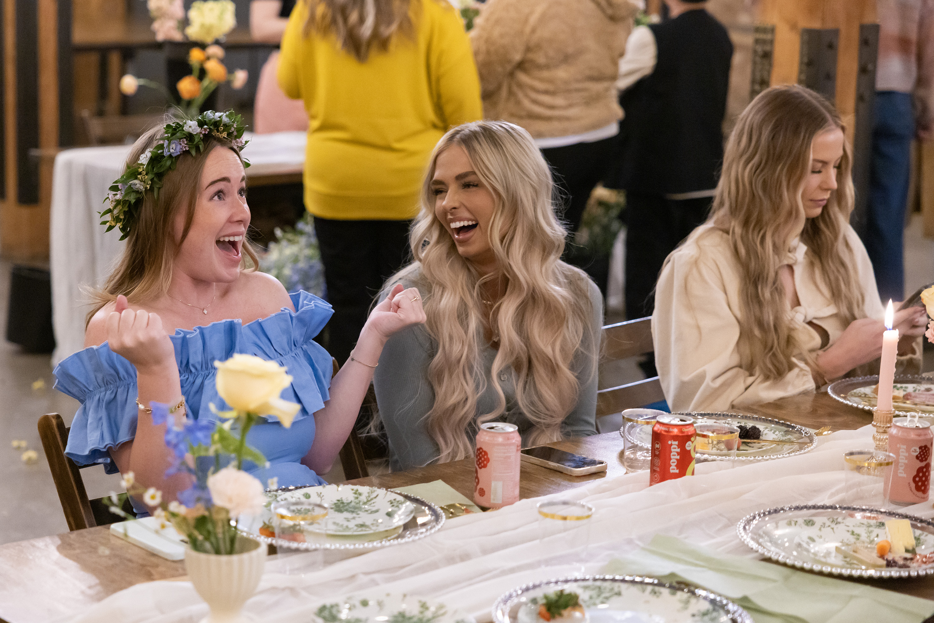 Three women (WHITNEY LEAVITT, MIRANDA MCWHORTER, MAYCI NEELEY) sit at a dinner table during a baby shower, in 'The Secret Lives of Mormon Wives' season 2.