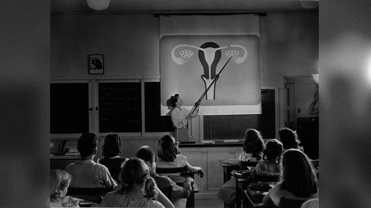 A teacher points to a diagram of female reproductive organs projected on a screen in a classroom in a scene from Human Growth, an education film on sex education shown to students in Oregon junior high schools beginning in 1948.