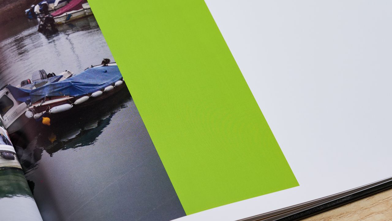 Vista Print photo book open on page with photo of boat and block of solid green