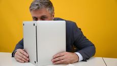 Mature man peeking out from behind laptop