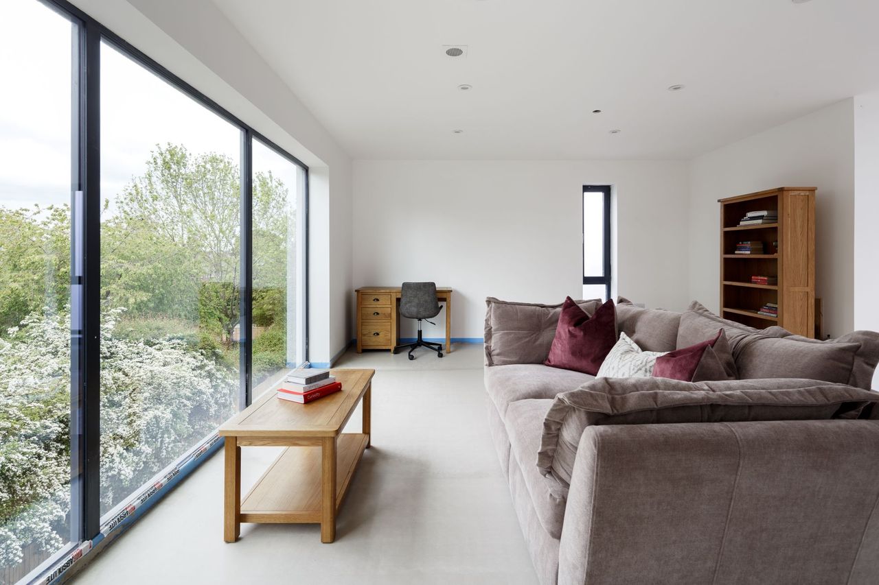 The upstairs living room includes an office area and is again next to large windows which the sofa looks out onto