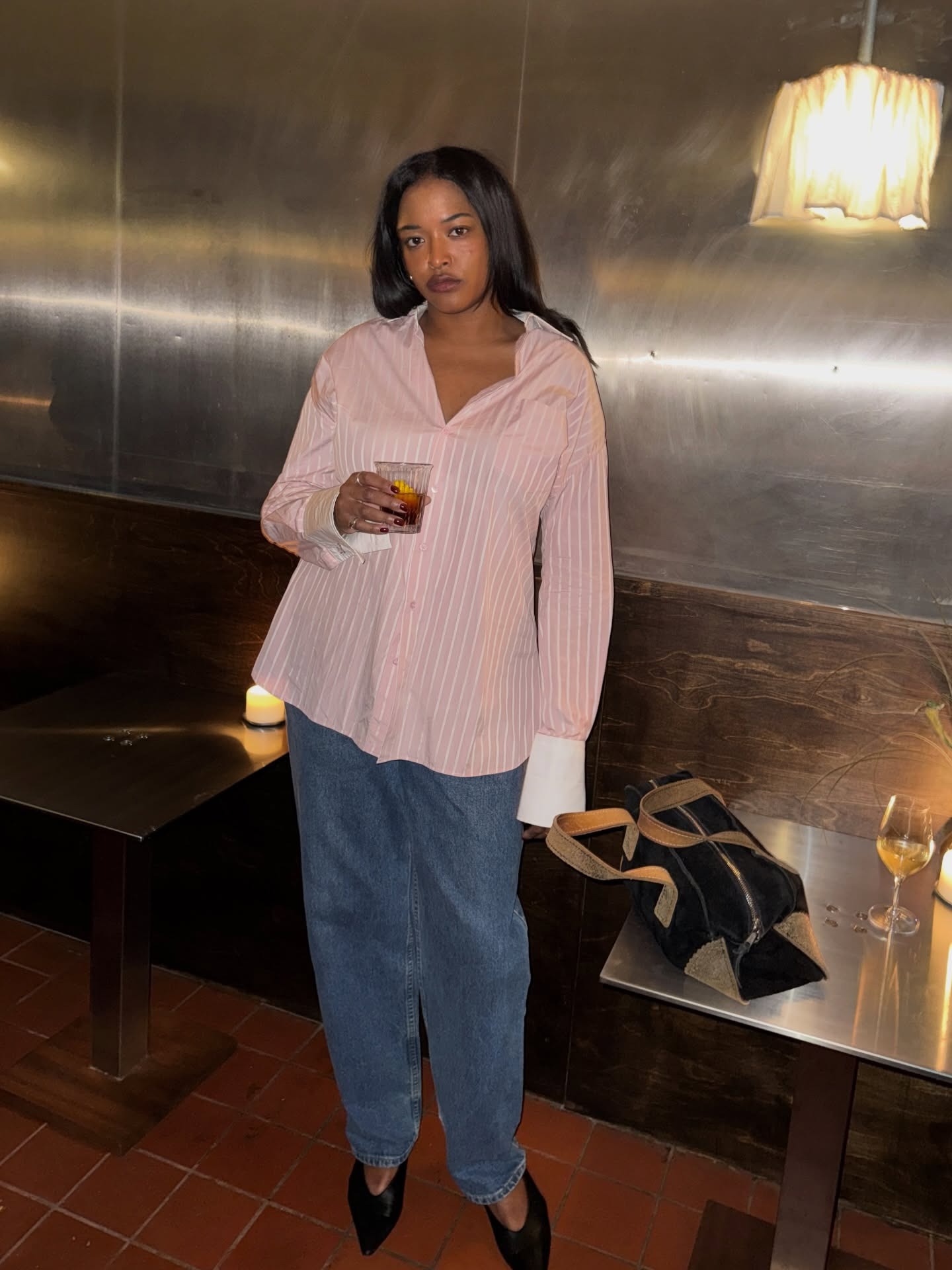 Imani Randolph wearing a pink button-down shirt with mid-wash mom jeans.