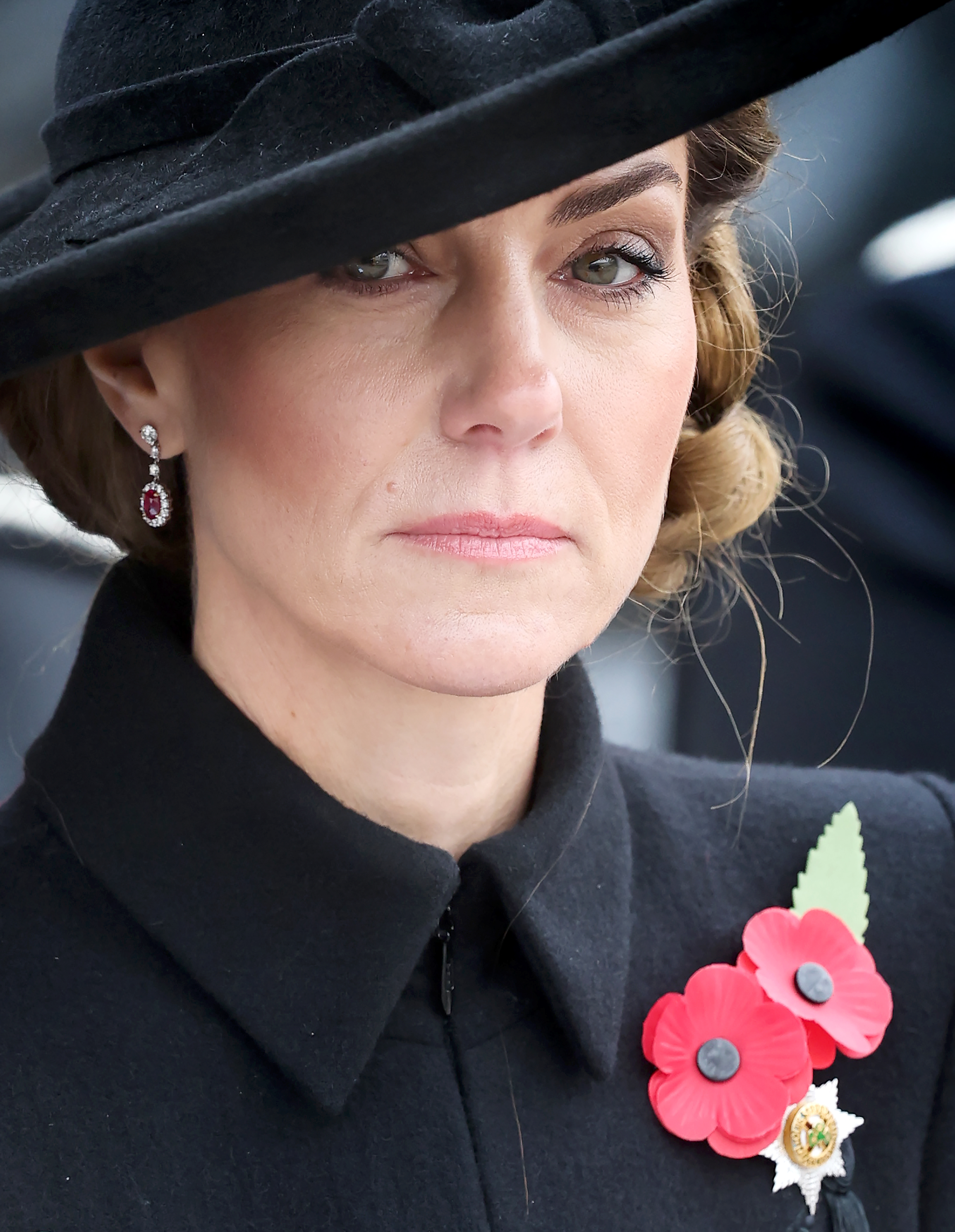 Kate Middleton wearing a black coat with red poppy pins on it