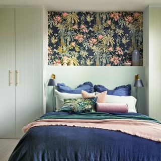 small bedroom with bespoke made to measure fitted furniture above and either side of the bed with a panel of floral wallpaper in between