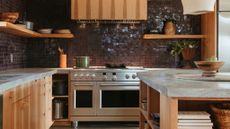 wood kitchen with small brown glazed tiles and stainless steel hob and oven