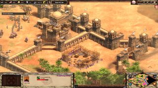 A desert town in Age of Empires 2 with plenty of walls, more structures are being constructed within