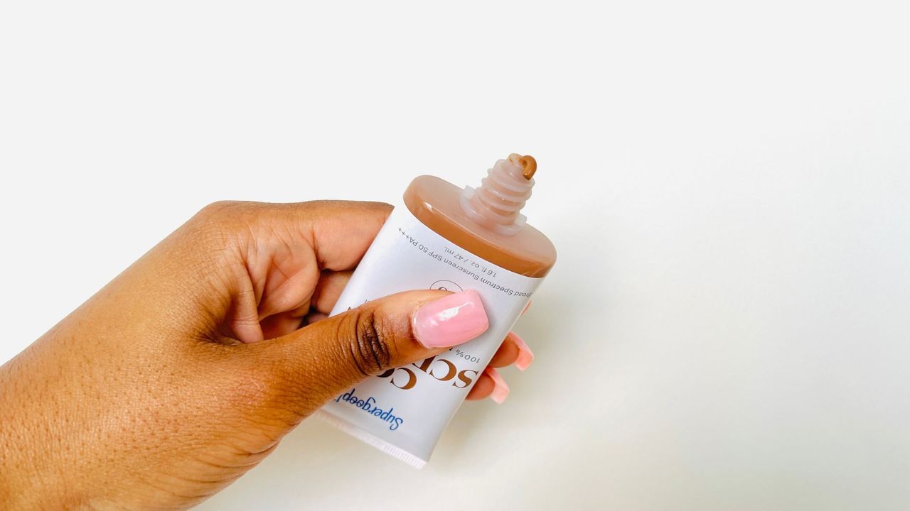 A person squeezing Supergoop! CC Screen SPF 50 PA squeeze tube for the best tinted moisturizers with SPF.
