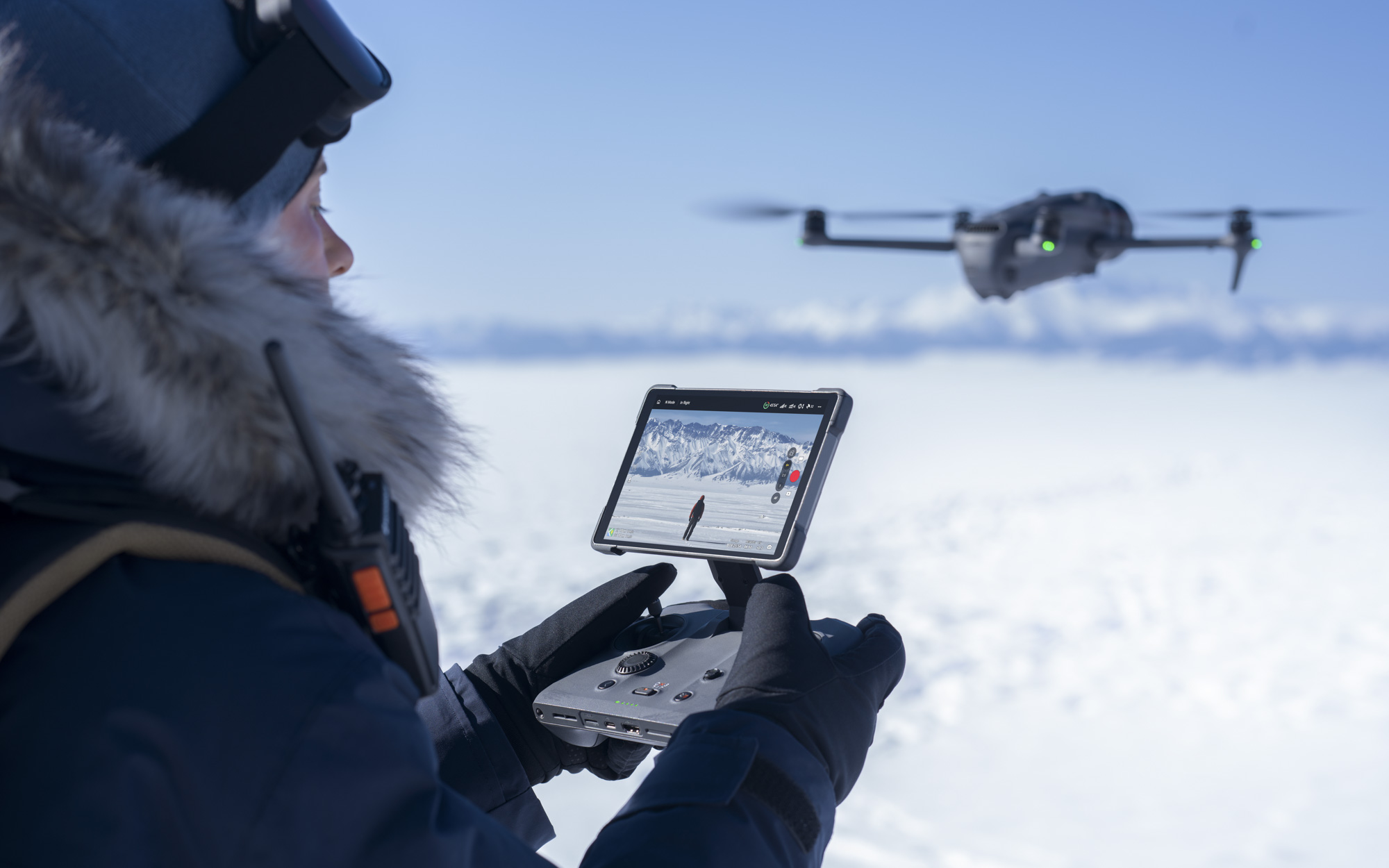 DJI Mavic 4 Pro drone in flight in background, with pilot controlling it using new controller in foreground