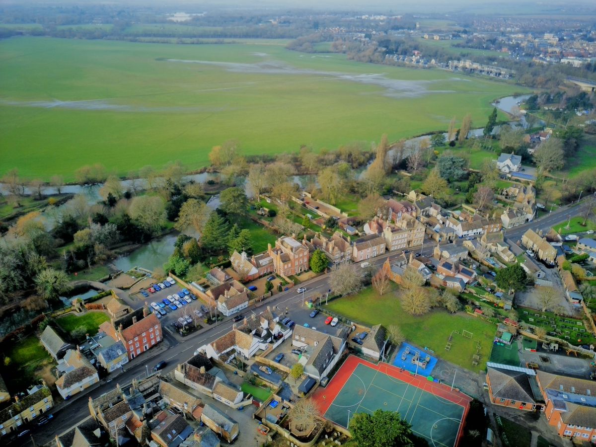Drone shot of a suburban street backing onto a large green field