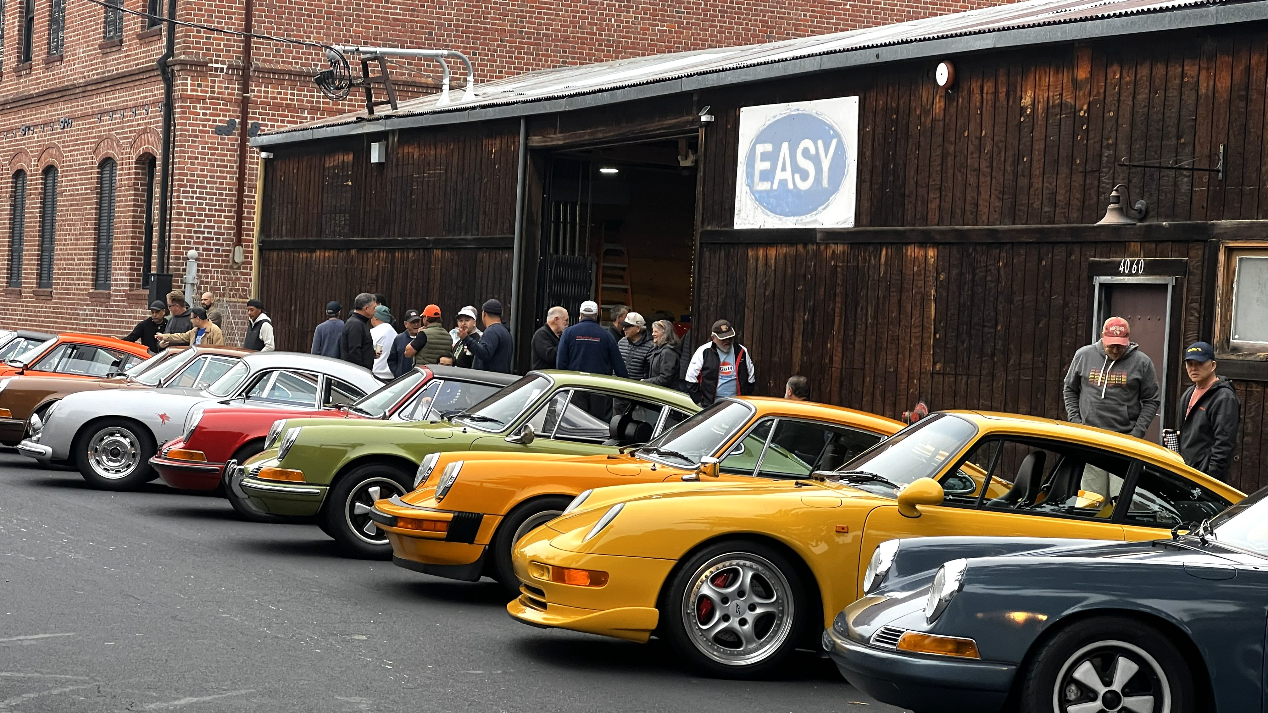 Colorful classic cars lined up at a car show under an "Easy" sign.