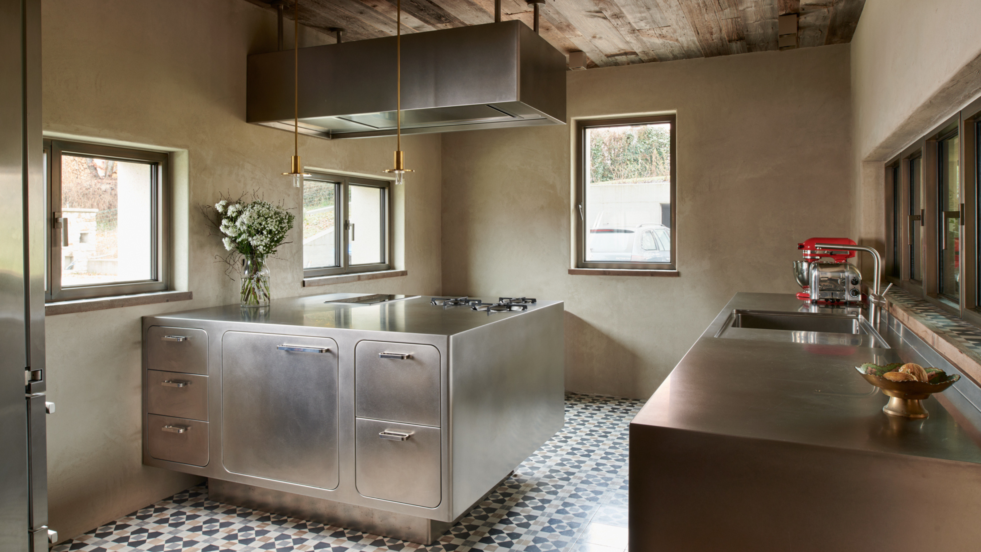 a beautiful stainless steel kitchen with gold detailing, ceramic tile floors, and neutral walls
